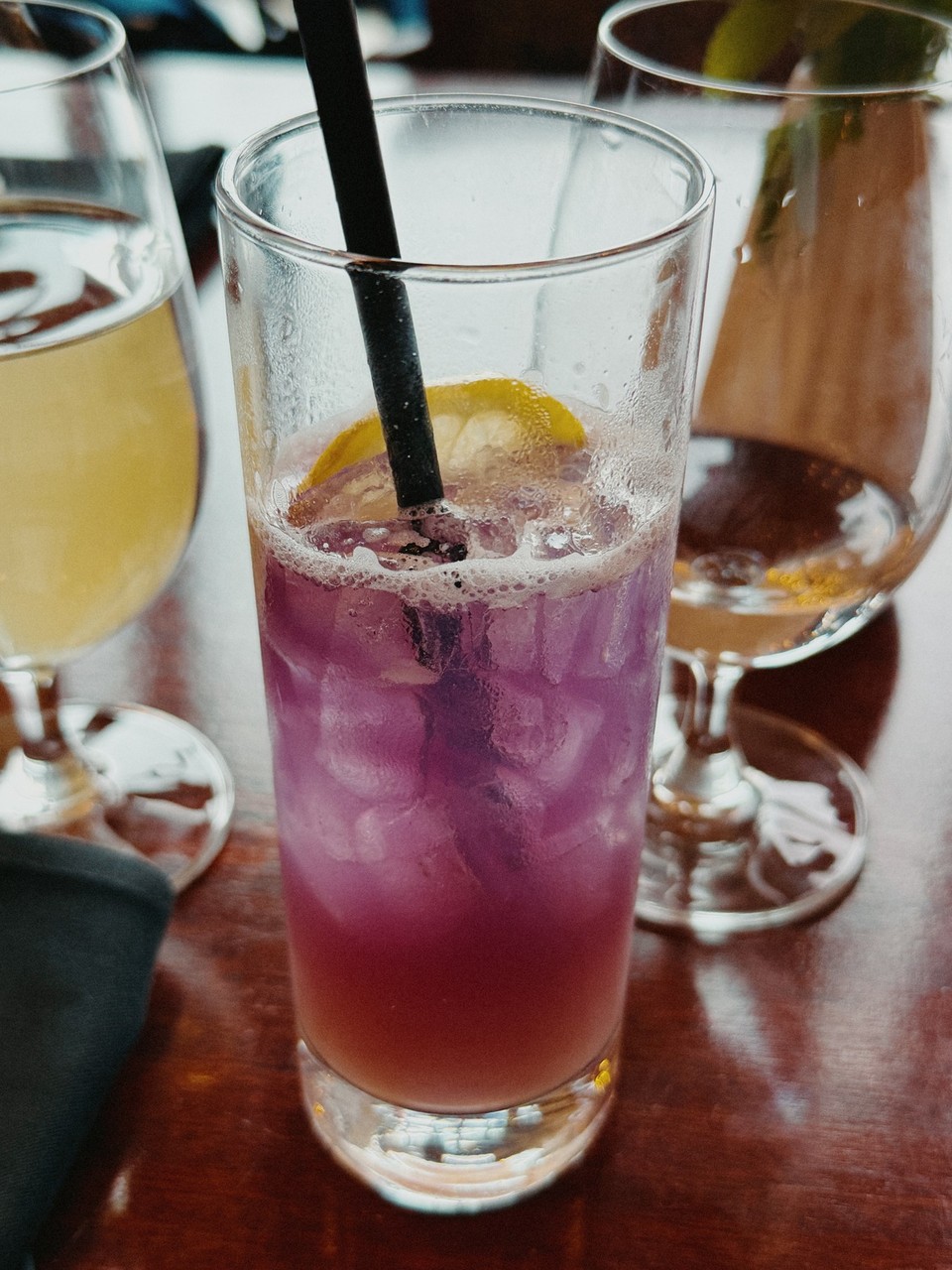 A purple drink with a lemon slice and condensation on the glass