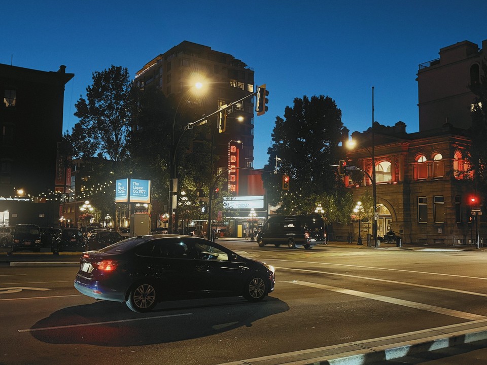 Cinema lights and passing cars at a city intersection at dusk
