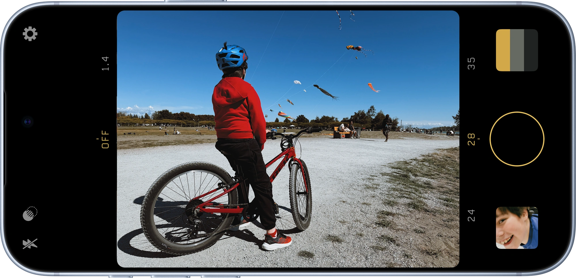 Filmcurve on iPhone, framing a child with a bicycle beneath a sky full of kites