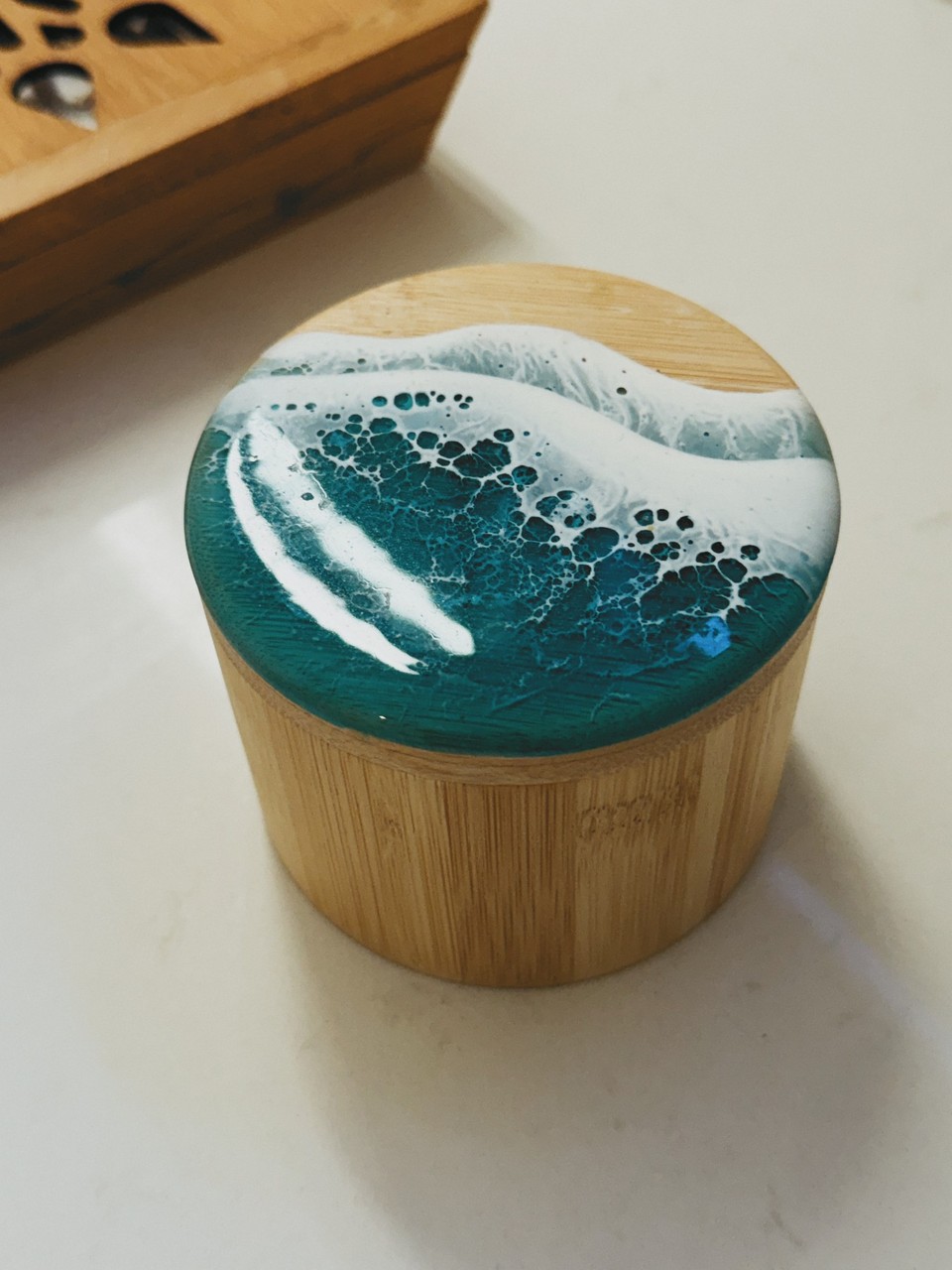 A wooden container with a turquoise ocean-wave resin lid