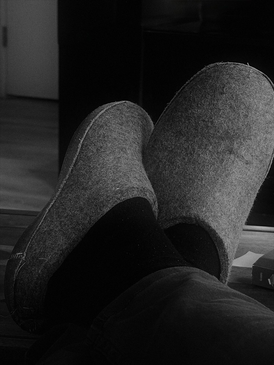 Feet resting in felt slippers, photographed in black and white