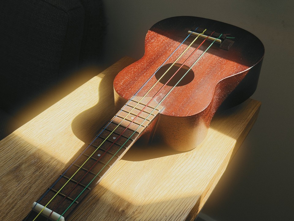 A ukulele with colourful strings in a shaft of afternoon sunlight