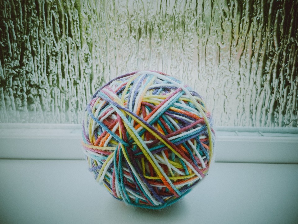 A ball of multicoloured yarn against textured window glass